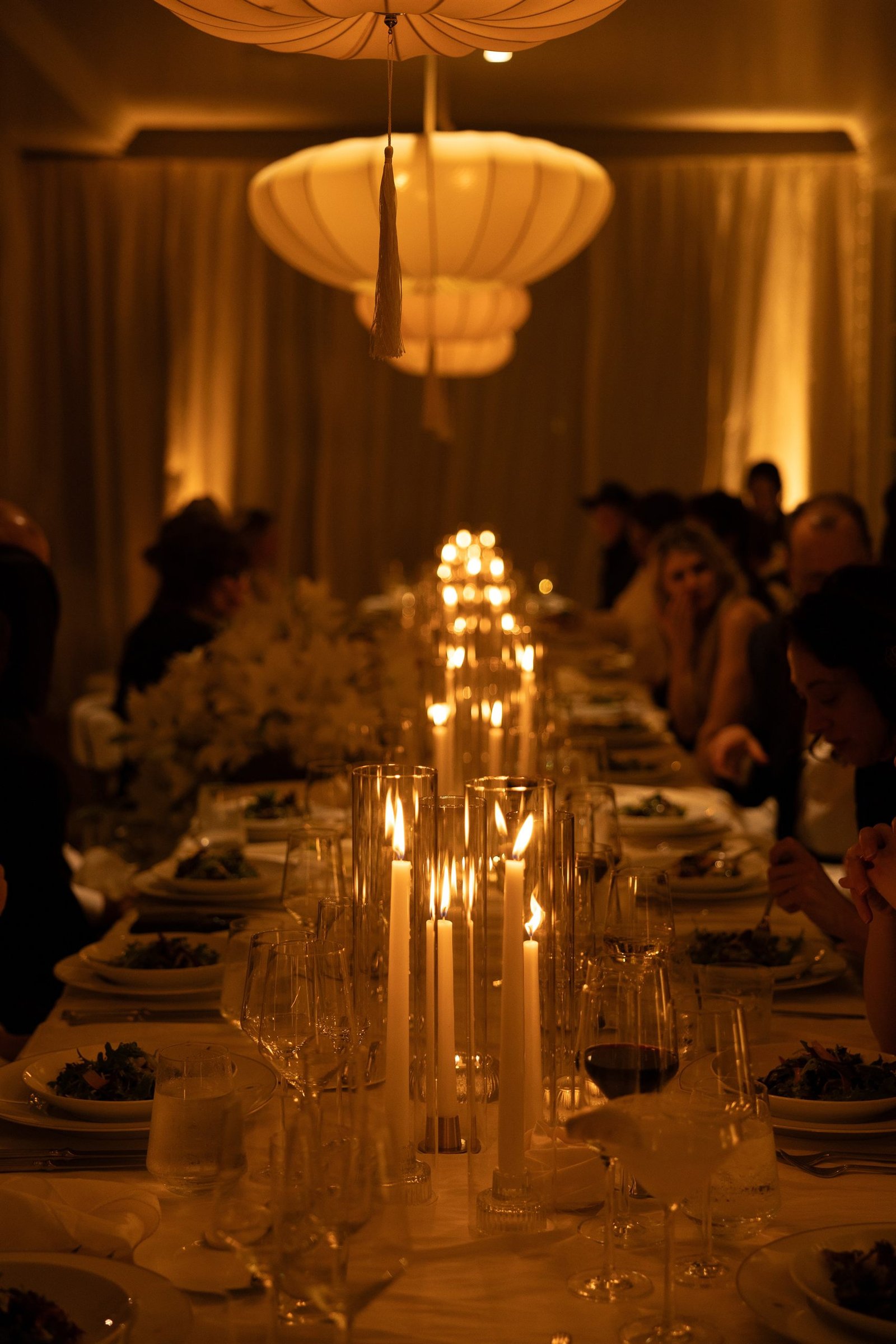 The black-tie wedding dinner table at Rosewood Miramar Beach, lit end to end by candles.