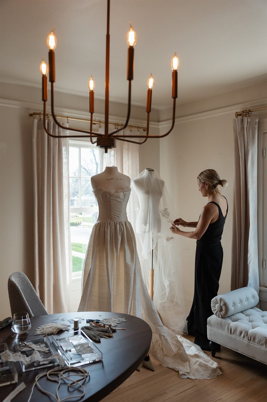 Brittany Casta&ntilde;os, dressed in black, working on the unfinished Montecito gown where it hangs on a dress stand.