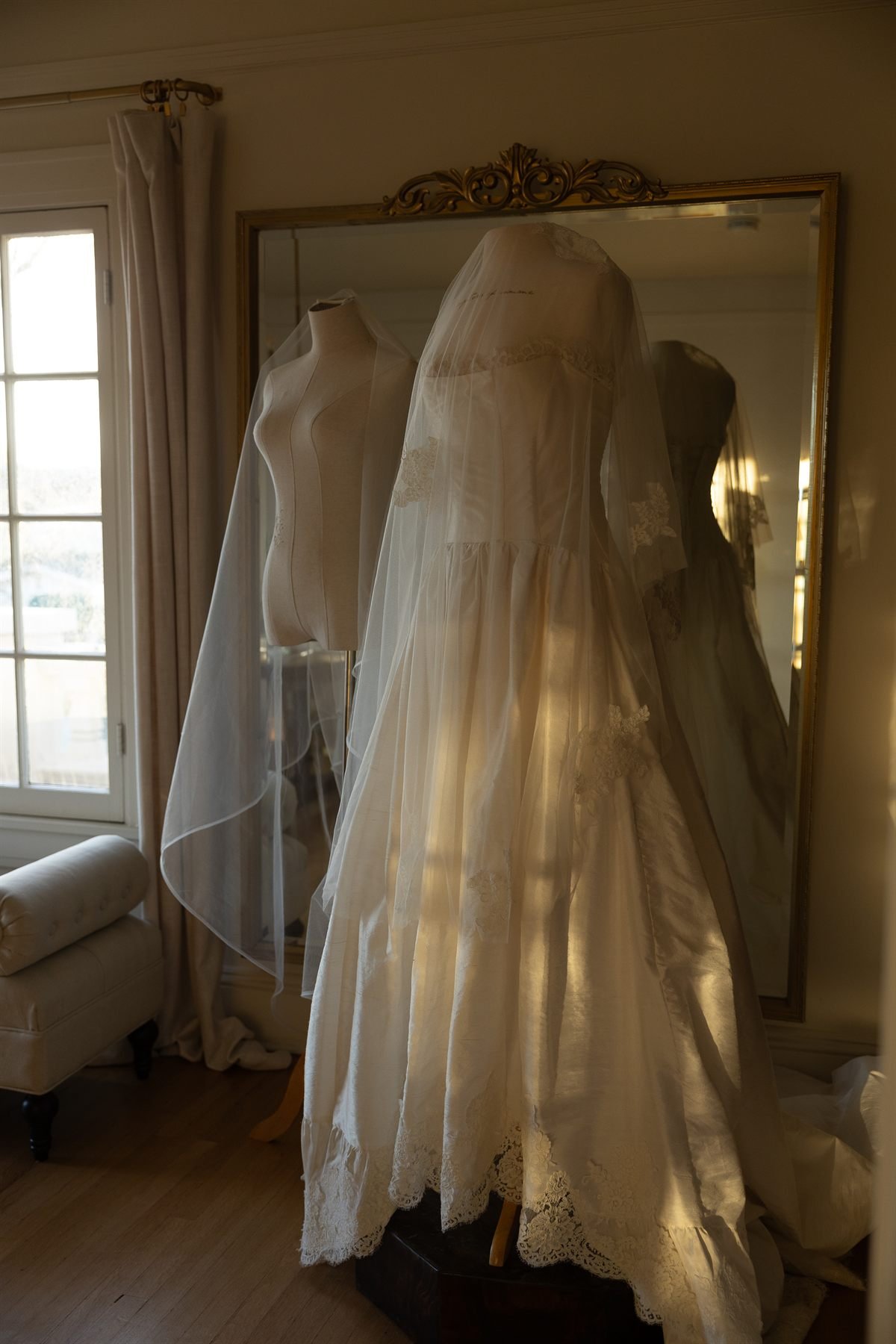The Montecito gown and Mural veil hanging on dress forms in a mirrored room at the Santa Barbara Inn before the ceremony.