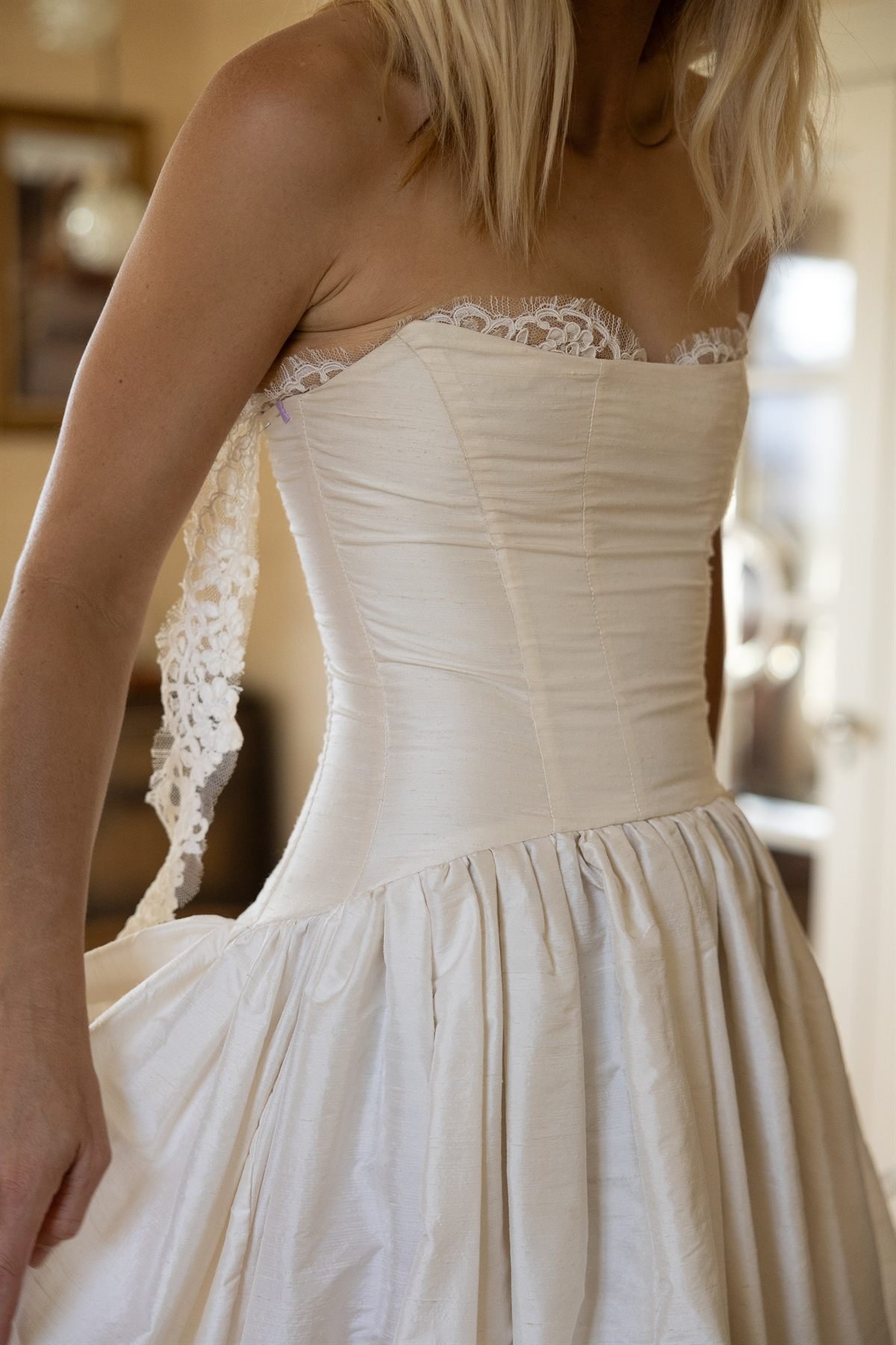 Close view of the Montecito gown&rsquo;s dropped waist and silk dupioni bodice with exposed lace trim at the front.