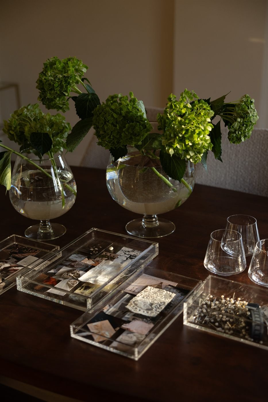 Trays of lace trims, beading and trim samples gathered for the Montecito gown beside vases of green hydrangea.