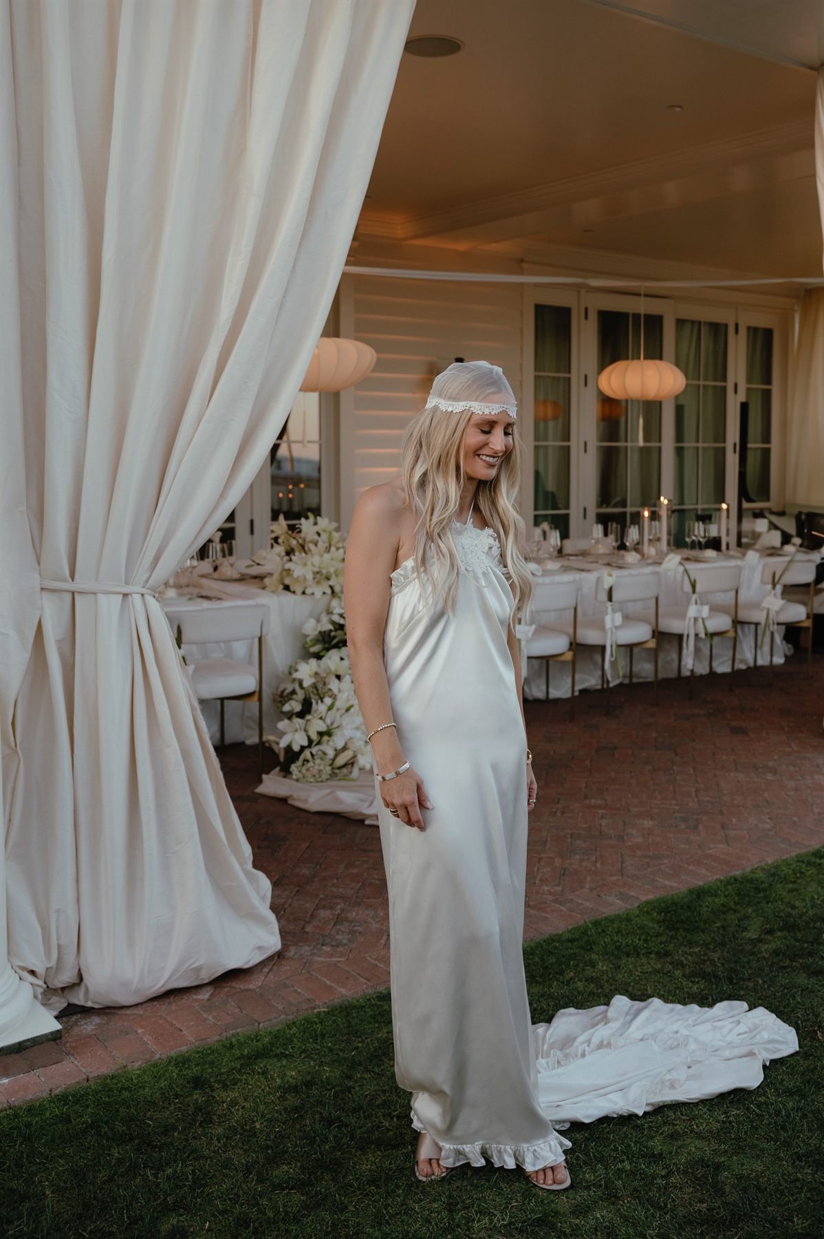 The bride in the archived Kate silk halter gown and Hallie veil on the lawn at Rosewood Miramar Beach.
