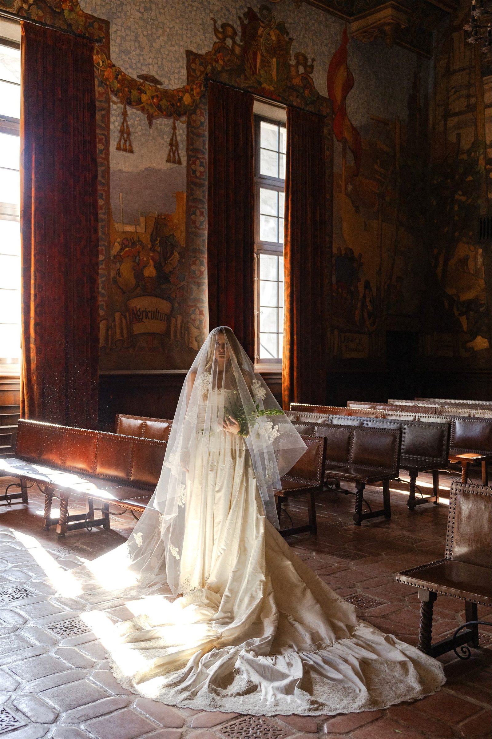 Brittany Casta&ntilde;os stands veiled in the Mural Room of the Santa Barbara Courthouse, the train of her Montecito gown fanned across the tiled floor in window light.